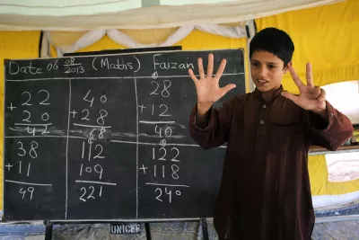 A boy (12) solves the math sums on the blackboard during his class in UNICEF-supported camp schools. Pakistan