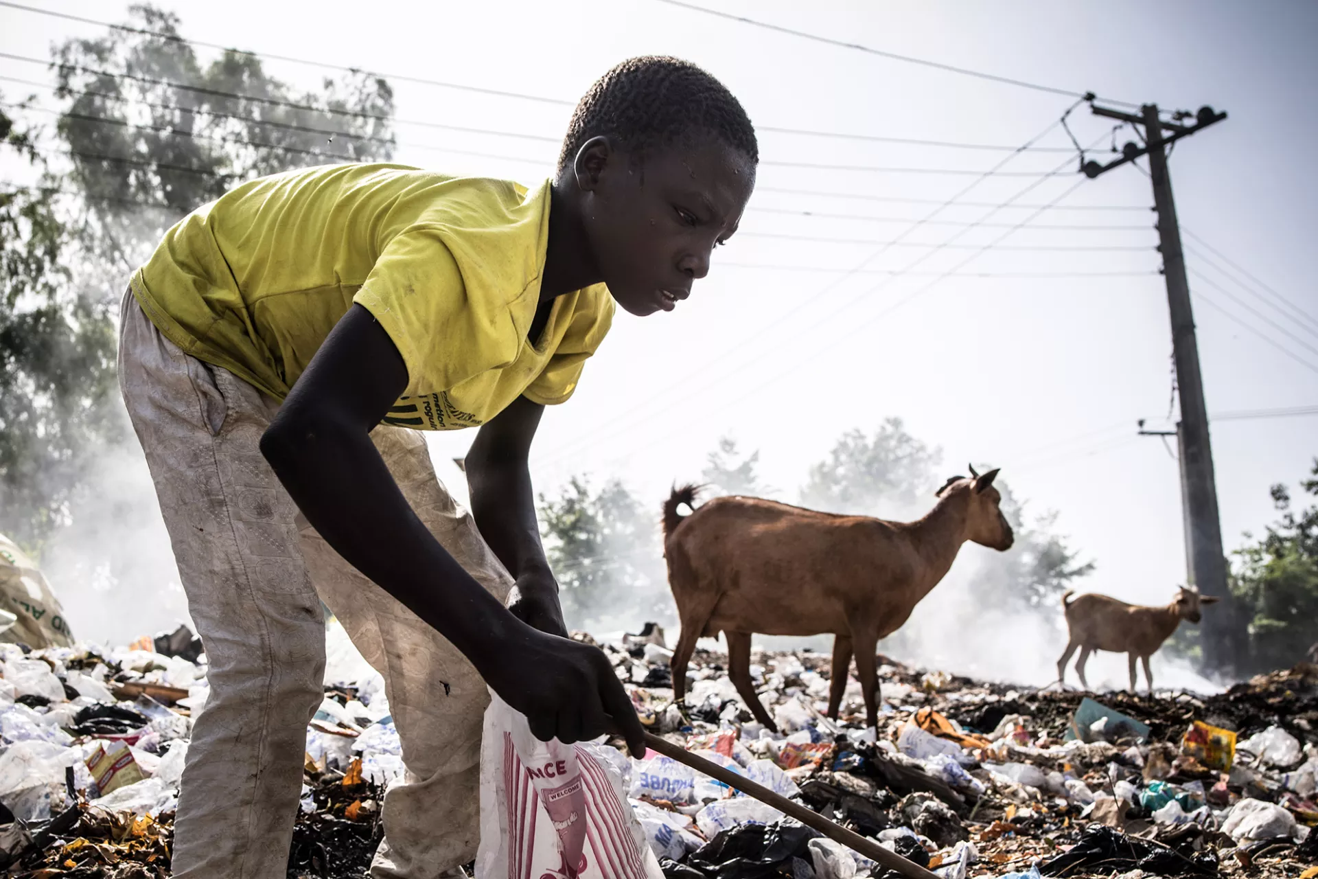 An adolescent boy digs through a rubbish dump for saleable items, Nigeria